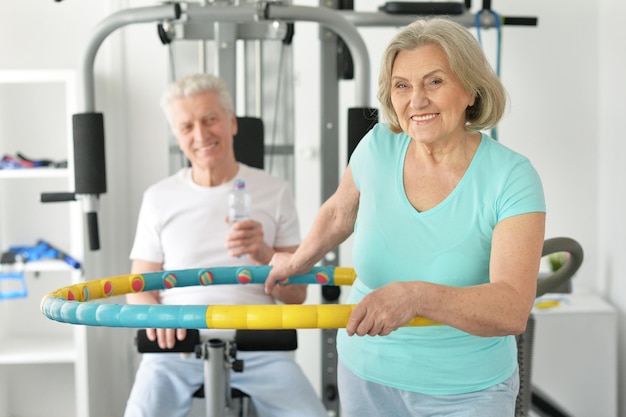 Aktives lächelndes älteres Paar, das im Fitnessstudio trainiert