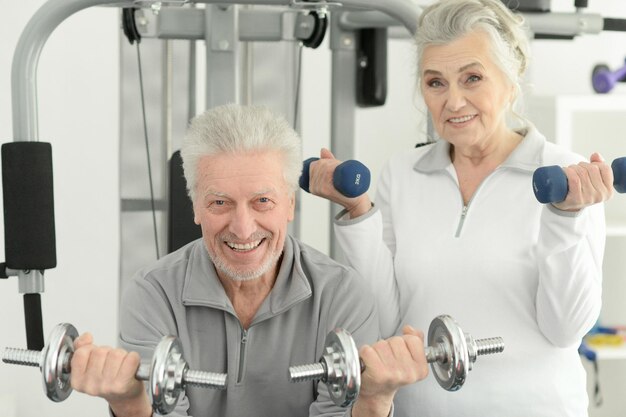 Aktives lächelndes älteres Paar, das zusammen im Fitnessstudio trainiert