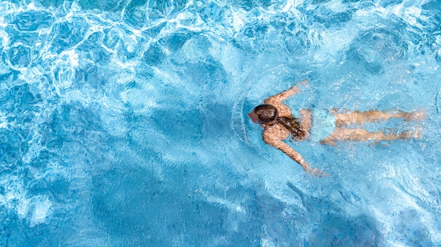 Foto aktives mädchen im schwimmbad, drohnenaufnahme von oben, junge frau schwimmt im blauen wasser