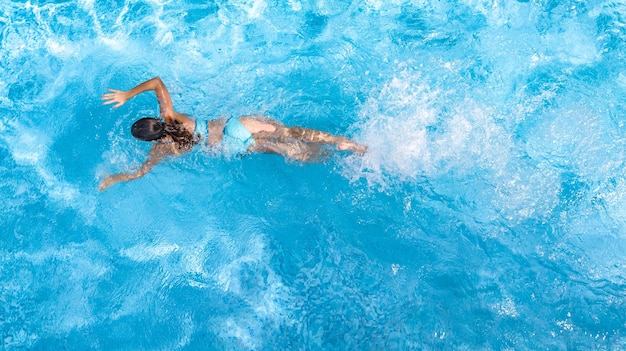 Foto aktives mädchen im schwimmbad luft-drohnenansicht von oben junge frau schwimmt im blauen wasser