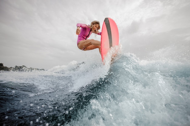 Aktives Teenager-Mädchen, das auf das orange Wakeboard springt