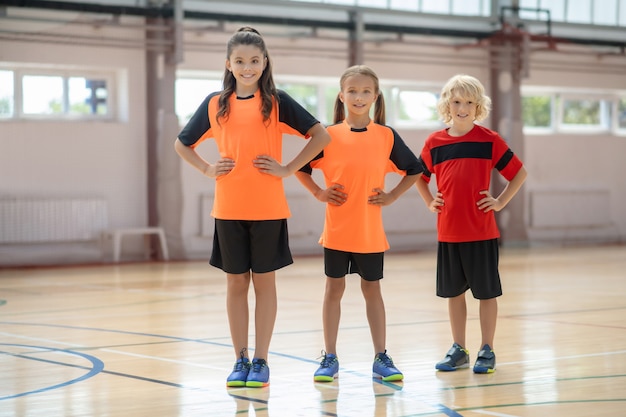 Aktiviert. Kinder in heller Sportbekleidung stehen mit den Händen auf den Hüften