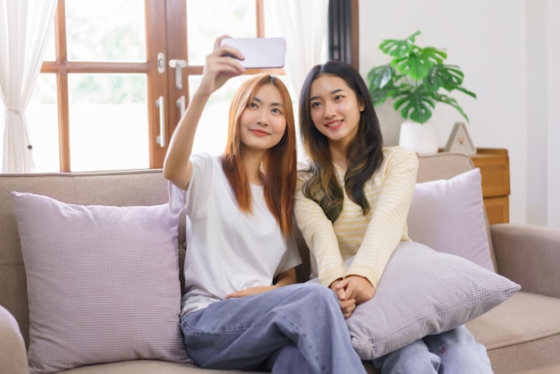 Aktivität zu Hause Konzept LGBT-lesbisches Paar lächelt und benutzt Smartphone, um sich gemeinsam zu selfie