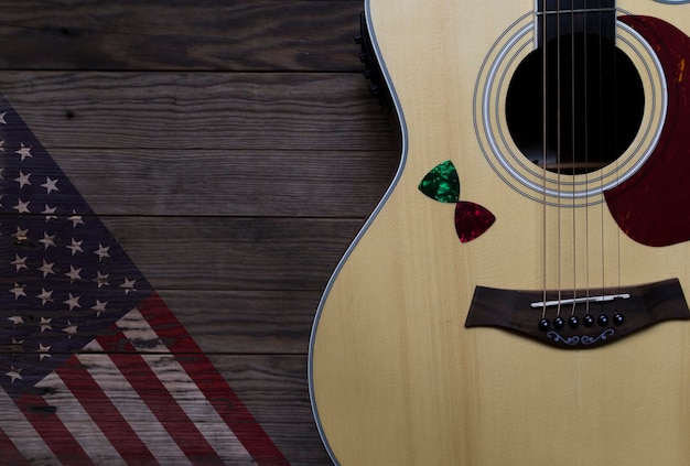 Akustische Gitarre platziert auf einem alten Holztisch mit einem Bild einer amerikanischen Flagge auf Holz Closeup