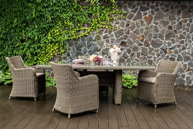 Foto al aire libre hecho de muebles de ratán con una mesa servida y sillas en la terraza