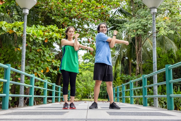 Al aire libre, en el puente, una atractiva pareja joven fitness estiramiento, un chico y una mujer deportivos haciendo ejercicio juntos.