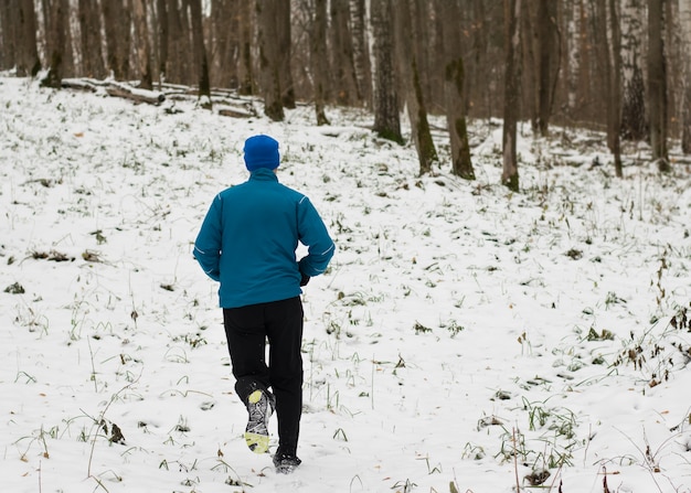 Al hombre le gusta correr en el bosque de invierno.