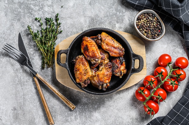 Al horno glaseado de alitas de pollo en una sartén. Fondo gris