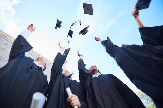 Al próximo capítulo de nuestras vidas Toma en ángulo bajo de un grupo de estudiantes lanzando sus gorras al aire el día de la graduación