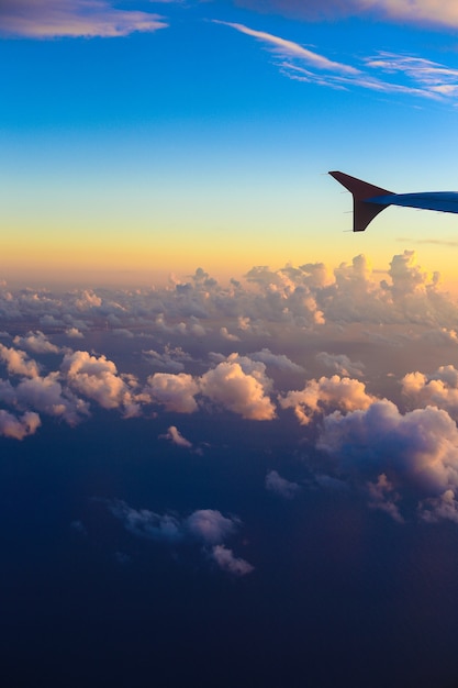 Ala de avión en el cielo del atardecer sobre el océano o el mar.