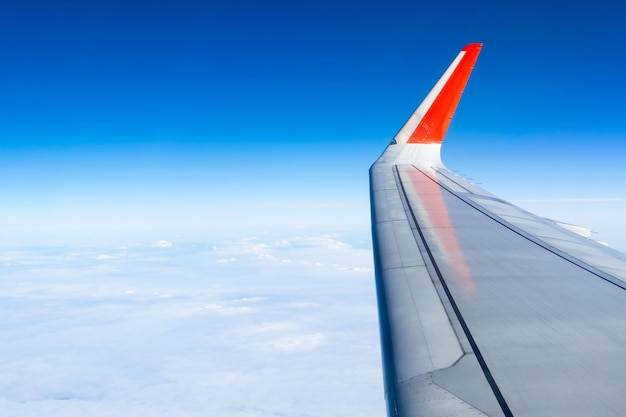 Ala de avión con cielo azul claro y nubes blancas sobre el concepto de viaje o vacaciones en tierra de verano