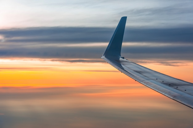 Ala del avión iluminado por el cielo del amanecer.