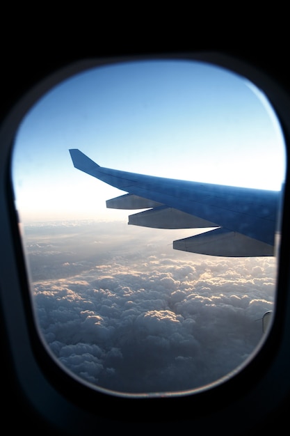 Ala de avión en ojo de buey sobre las nubes al atardecer.