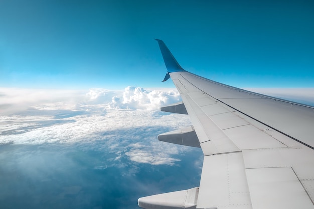 Un ala de un avión de pasajeros moderno sobre las nubes. Transporte de carga internacional, transporte aéreo, transporte. Copie el espacio.