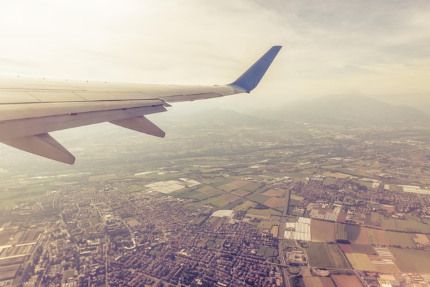 Ala de un avión que vuela por encima de ciudades y pueblos