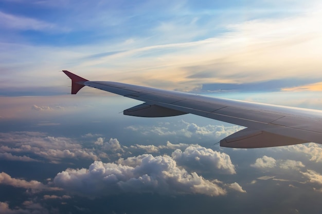 Ala de un avión que vuela sobre las nubes de la puesta del sol Mira el cielo desde la ventana del viaje aéreo del avión