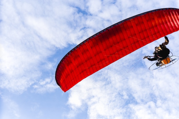 Ala flexible del motor que vuela en cielo azul con la nube blanca en fondo.