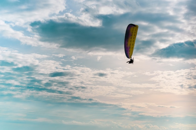 Ala flexible del motor que vuela en cielo azul con la nube blanca en fondo.