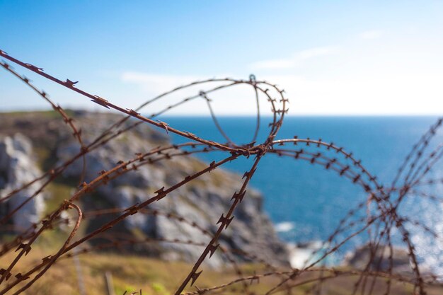 Alambre de púas en la valla con el océano Atlántico