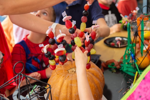 Alanya Türkei 29102022 Kinder auf einer Halloween-Party stecken Obststäbchen in einen Kürbis Kinder erfüllen die Aufgaben des Animators auf der Party