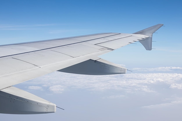 Las alas de un avión volando por encima de las nubes de la mañana.