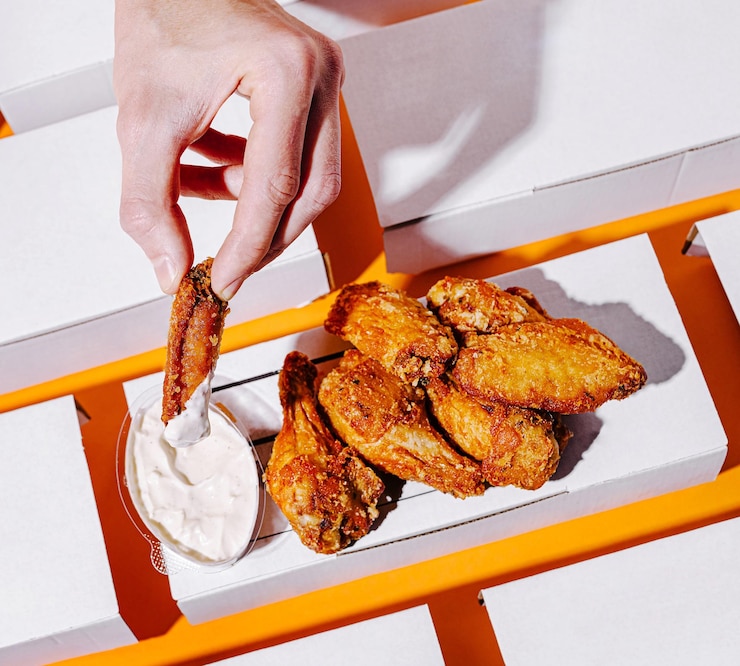 Alas de pollo crujientes servidas con salsa de inmersión en un fondo brillante