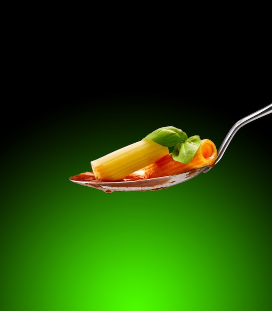 albahaca cerca de pasta y salsa de tomate en una cuchara