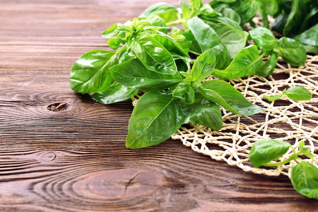 Albahaca fresca verde con soporte de mimbre en la mesa de cerca