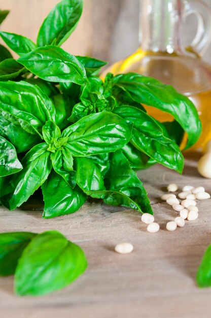 Albahaca orgánica verde fresca sobre una mesa de madera Y productos para ensalada tomates ajo piñones La foto está hecha en un estilo rústico con un fondo borroso