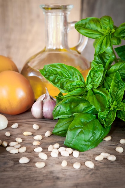 Albahaca orgánica verde fresca sobre una mesa de madera Y productos para ensalada tomates ajo piñones La foto está hecha en un estilo rústico con un fondo borroso