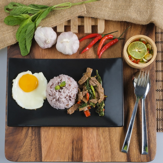 Foto albahaca de ternera salteada con huevo frito y arroz con arándanos.