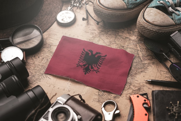 Albanien-Flagge zwischen dem Zubehör des Reisenden auf alter Weinlese-Karte. Touristisches Bestimmungsort-Konzept.