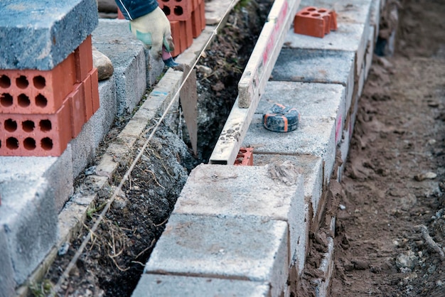 albañil colocando bloques de hormigón sobre cimientos de hormigón en un nuevo sitio de viviendas residenciales