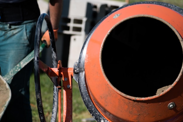 Albañil preparando hormigón con una mezcladora de cemento para construir un muro en un sitio de construcción