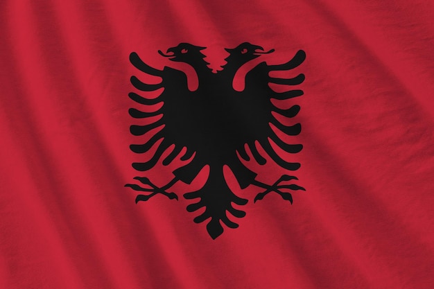 Albanische Flagge mit großen Falten, die in der Nähe unter dem Studiolicht im Innenbereich winken Die offiziellen Symbole und Farben im Banner