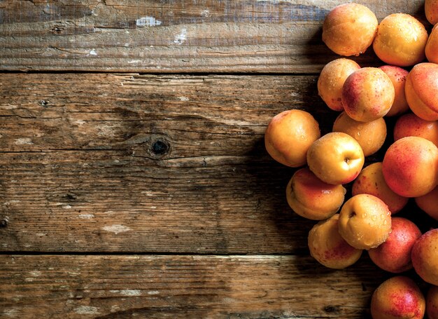 Albaricoque. Frutas orgánicas con hojas sobre fondo de madera