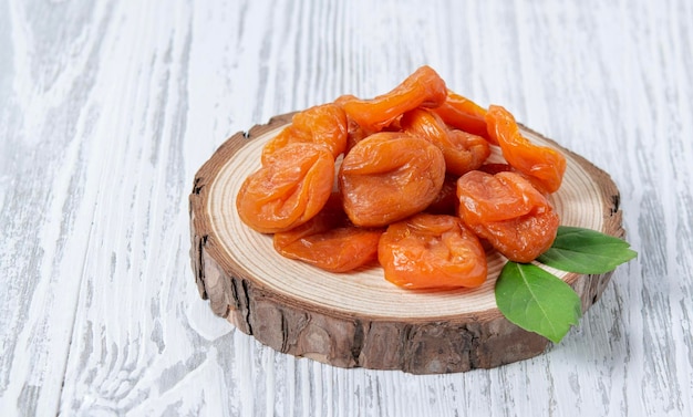 Albaricoque de frutas secas en una tabla de madera sobre un fondo de madera blanca Estilo rústico El concepto de bocadillos vegetarianos y dietéticos