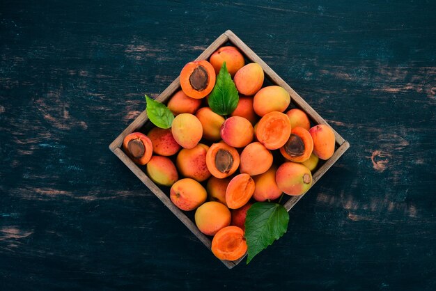 Albaricoques en una caja de madera Frutas frescas Sobre un fondo de madera negra Vista superior Espacio libre para su texto