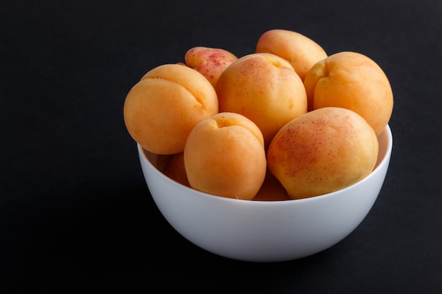 Albaricoques frescos de naranja en un tazón blanco