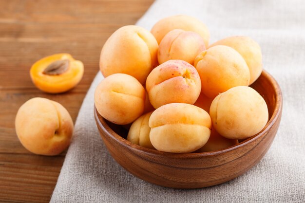 Albaricoques frescos de naranja en un tazón de madera