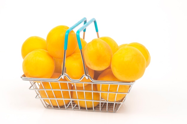 Albaricoques maduros en una cesta de la compra de un supermercado sobre un fondo blanco.