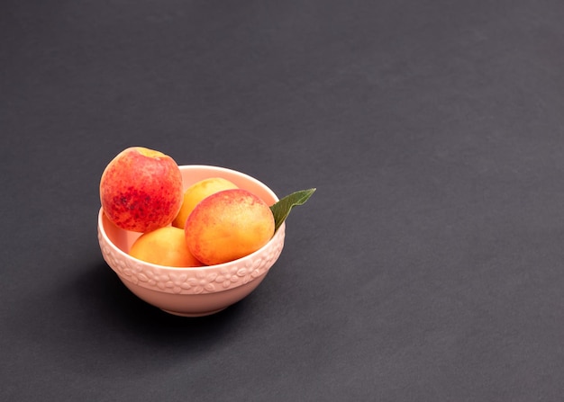 Albaricoques naranjas en un tazón contra un fondo oscuro Concepto mínimo de comida Espacio de copia