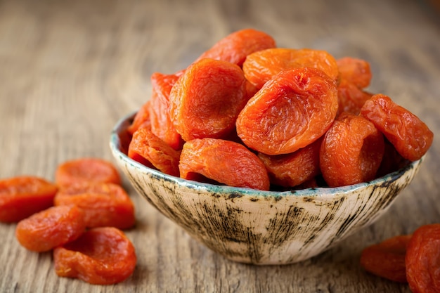 Albaricoques secos en un cuenco de bambú sobre una madera vieja. Frutos secos saludables