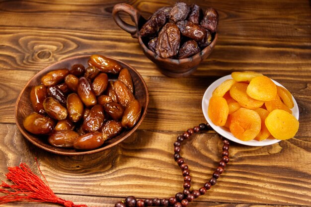 Albaricoques secos y dátiles con rosario de madera sobre mesa de madera La fiesta musulmana del mes sagrado del Ramadán