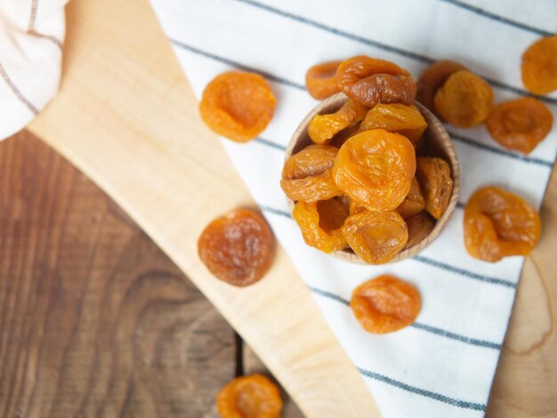 Albaricoques secos secos en un recipiente sobre una mesa de madera antigua frutos secos