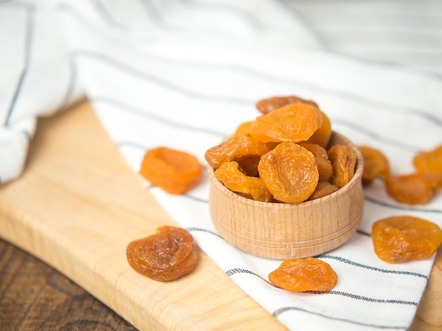 Albaricoques secos secos en un recipiente sobre una mesa de madera antigua frutos secos