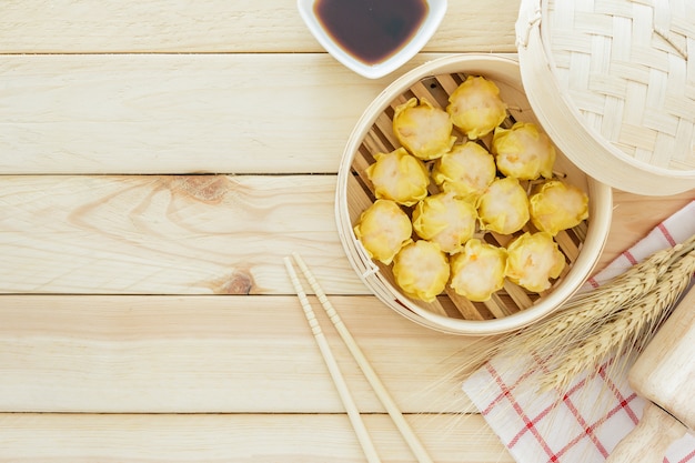 Albóndigas al vapor (dim sum chino) en canasta de bambú, servir con palillos en tabl de madera