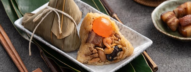 Albóndigas de arroz Zongzi para el Dragon Boat Festival sobre fondo de mesa gris oscuro con ingrediente