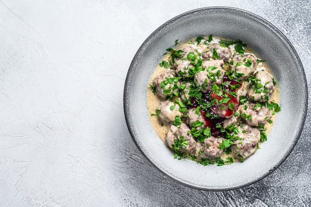 Albóndigas de carne molida con salsa de crema en un plato. Mesa de madera blanca. Vista superior.