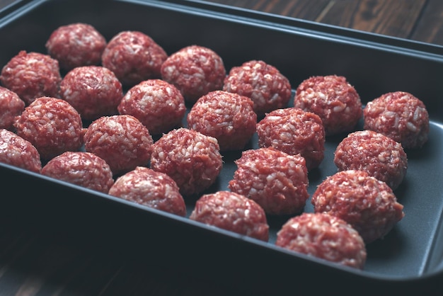 Las albóndigas crudas en las bandejas para hornear están preparadas y listas para hornear en el enfoque selectivo del horno